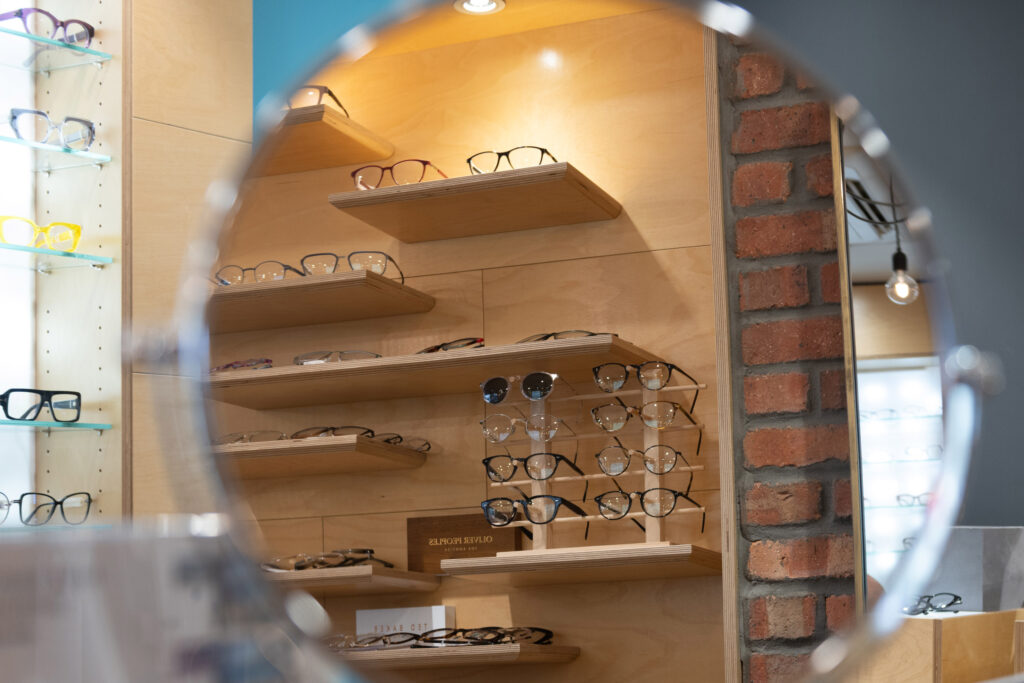 A round mirror reflecting a display of glasses