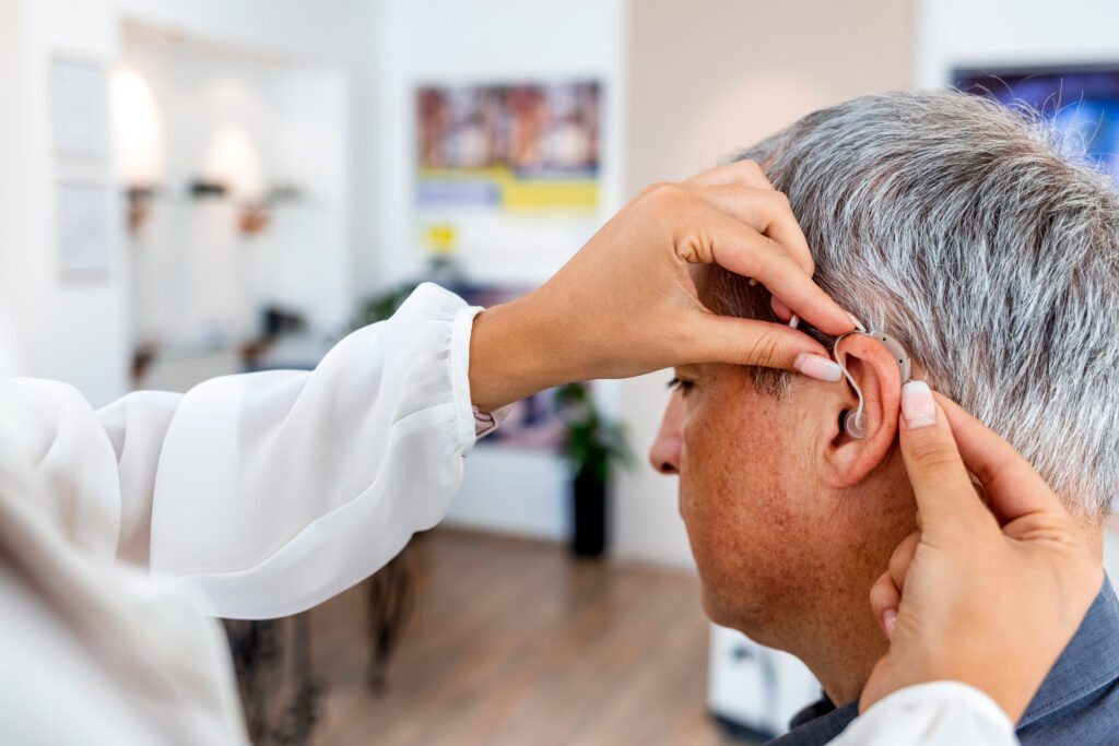 An elderly man having a hearing aid fitted